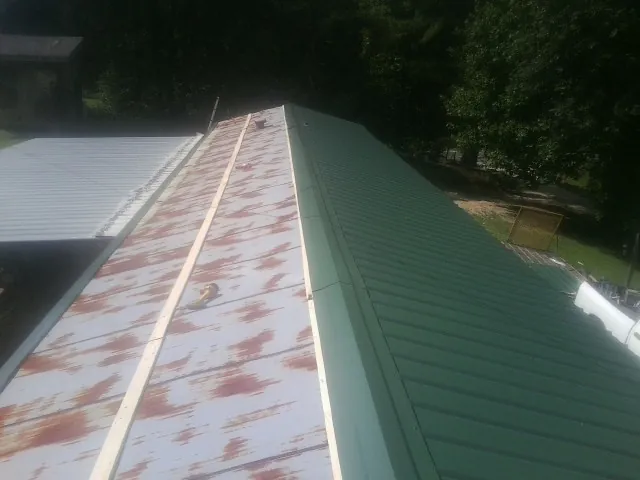 Old rusted panels beside newly installed green metal roofing — Wind Damage Roof Repair by Roofing Brothers in Newry
