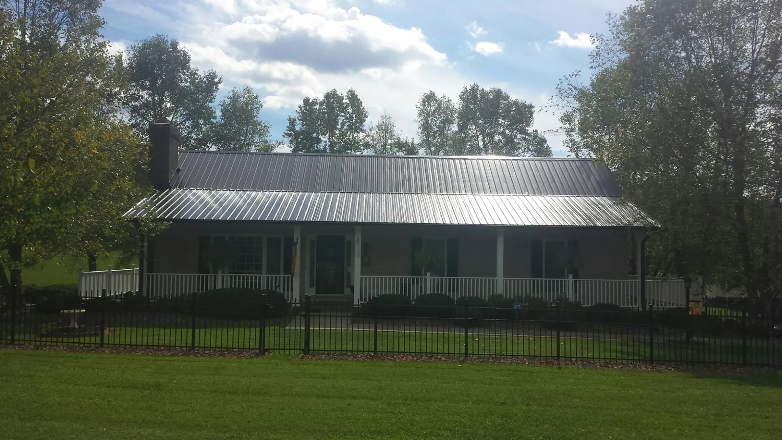 Gray metal roof on a brick ranch with a full width front porch — Gutter Guard Installation work by our crew in Newry
